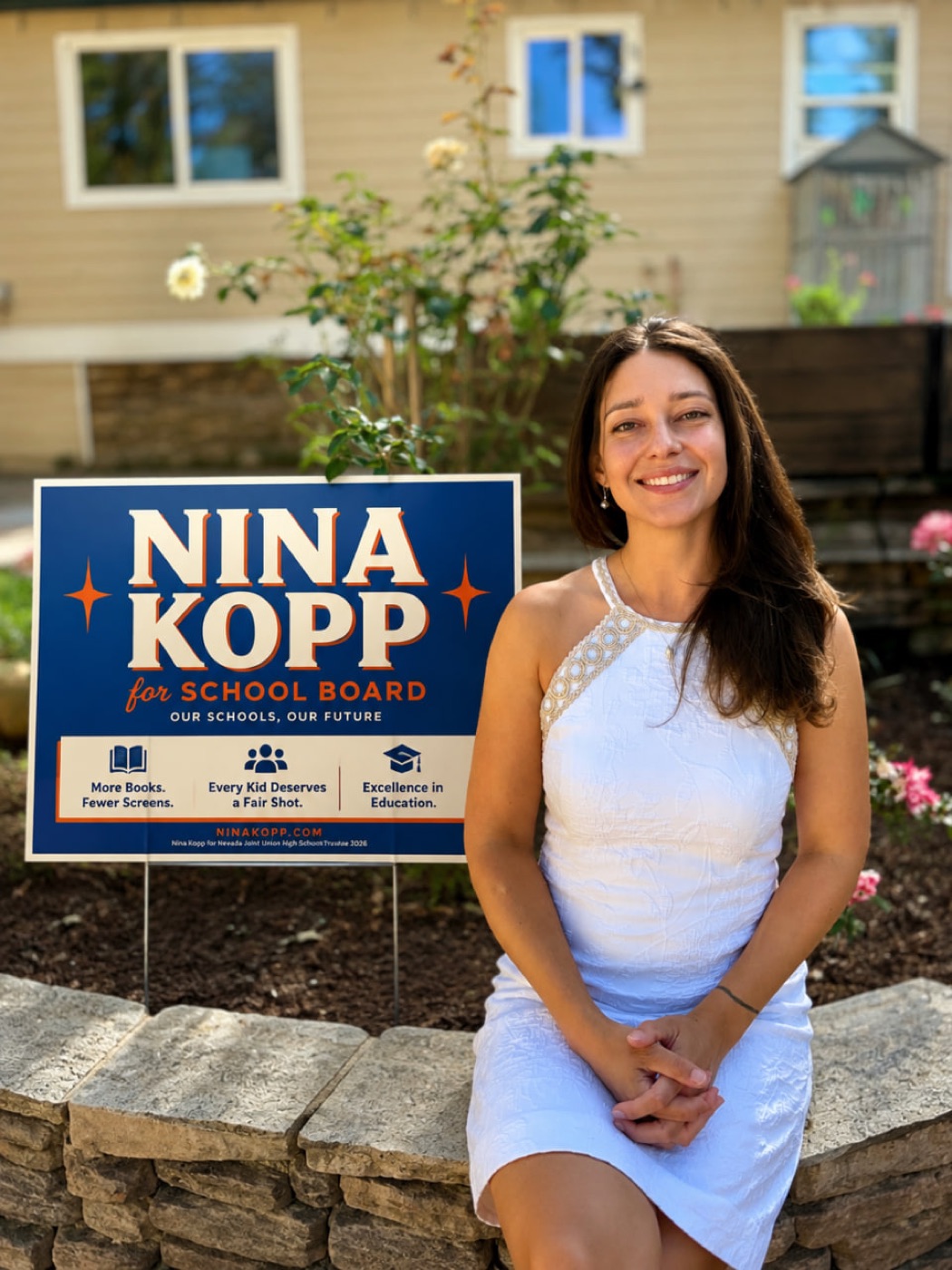 Nina Kopp seated beside her campaign yard sign